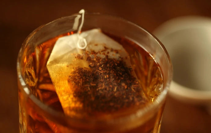 Tea bag steeping in a glass of hot water.